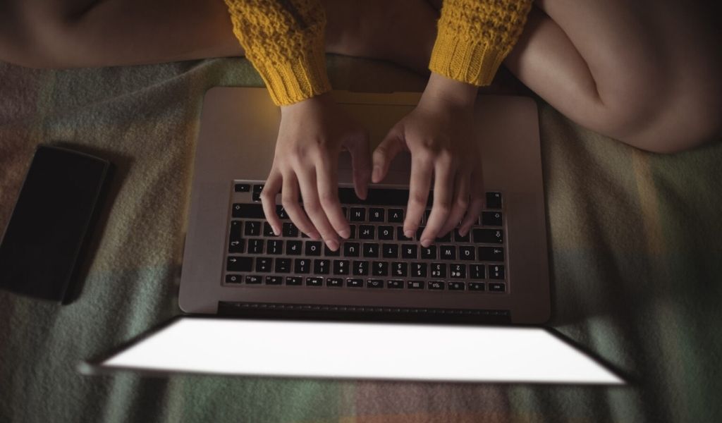 Woman using laptop in bed.